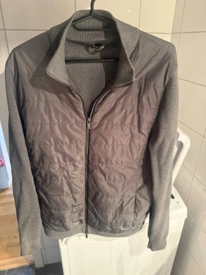 Massimo dutti cardigan  - Snygg grå cardiganjacka med quiltad framsida och stickade ärmar samt rygg. Jackan har dragkedja framtill och hög krage. Perfekt för lager-på-lager och en stilren look. Materialmix med både vadderad och stickad känsla.