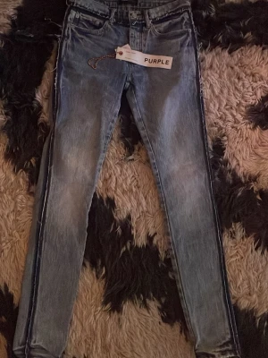 purple jeans med distressing på sidan - Säljer ett par blå skinny jeans från Purple med klassisk femficksmodell och slitna detaljer. Jeansen har en tvättad look med ljusare partier på låren och raka ben. Perfekta för en avslappnad och trendig stil.