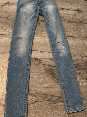 Ljusblå slitna jeans från Crocker - Säljer ett par ljusblå jeans från Crocker med skinny fit och slitningar på benen. Jeansen har klassisk femficksdesign och är gjorda i mjuk denim. Perfekta för dig som gillar en avslappnad och trendig stil.