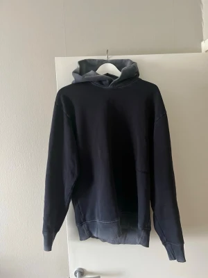 Alpha tauri hoodie - Snygg mörkblå hoodie med kontrasterande grå huva. Hoodien har en avslappnad passform, ribbade muddar vid ärmslut och nederkant samt en klassisk look utan synligt tryck eller logga. Perfekt för en chill och stilren vardagsoutfit.