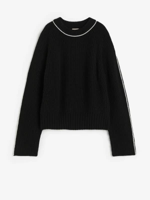 Svart stickad tröja med vita detaljer - Svart stickad tröja med ribbad struktur och vita ränder längs ärmarna samt en vit kant runt halsen. Tröjan är från h&m i storlek s.❤️