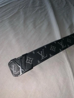  bälte med monogram - Snyggt svart bälte  med klassiskt monogrammönster. Bältet har en stilren design och är tillverkat i skinn med detaljer i silverfärg. Perfekt accessoar för att lyfta din outfit.