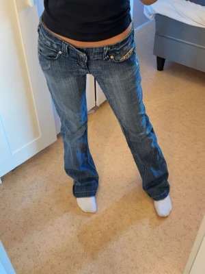 Blåa lågmidjade jeans från River Island - Säljer dessa blåa lågmidjade jeans från River Island, med snygga sten-detaljer på både fram och baksida. Säljs då de inte kommer till använding. Finns kvar tills markerat sålt!💕 Har inget måttband så kan inte räkna ut måtten tyvärr! Men som sagt sitter de som S. 💘