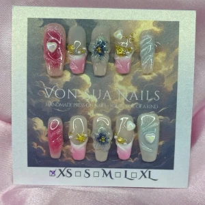 CloudKiss (XS);Medium Ballerina - Handgjorda press-on naglar i mixade färger som rosa, nude och vitt. Dekorerade med 3D-blommor, små hjärtan och guldfärgade detaljer. Naglarna har en elegant, medium lång ballerina form och glansig finish. Perfekt för dig som vill ha unika och kreativa naglar.