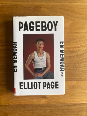 Pageboy: En memoar av Elliot Page - En stark och personlig memoar av Elliot Page. Boken har ett vitt omslag med svart text och ett foto på författaren på framsidan. Inbunden och utgiven av Natur & Kultur. Perfekt för dig som gillar självbiografier och gripande livsberättelser.