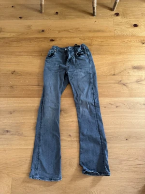 Grå bootcut jeans från Gina Tricot - Säljer ett par grå bootcut jeans från Gina Tricot. Storlek 164 & bra skick. Har någon fläck på ena benet ( se bild 3) men går förmodligen bort i tvätt