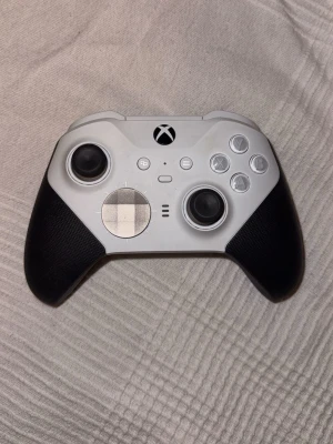 Xbox Elite Series 2 handkontroll - Snygg Xbox Elite Series 2 handkontroll i svart och vit med gummerade grepp, metalliska styrplattor och klassiska Xbox-knappar. Perfekt för gaming med avancerade funktioner och ergonomisk design.