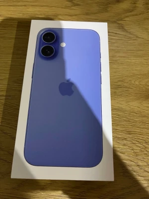 Lila iPhone 16 med dubbla kameror - Säljer en snygg lila iPhone 16 från Apple. Telefonen har en stilren design med rundade hörn, två bakre kameror och Apples logga på baksidan. Materialet är glas och aluminium, vilket ger en premiumkänsla. Perfekt för dig som vill ha en modern och färgglad mobil.
