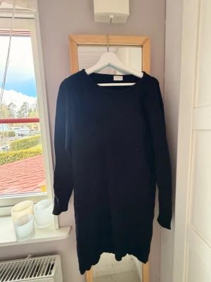 Svart stickad klänning från Aéryne - En svart stickad klänning från vila med rund halsringning och långa ärmar. Klänningen har en rak passform och ribbstickade detaljer vid ärmslut och nederkant. Perfekt för lager-på-lager och enkel att styla.