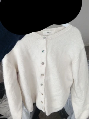 Vit kofta från Gina Tricot - Mysig vit kofta från Gina Tricot med rund halsringning och knappar framtill. Koftan är stickad och har långa ärmar samt ribbade muddar vid ärmslut och nederkant. Perfekt för lager-på-lager och enkel att matcha.