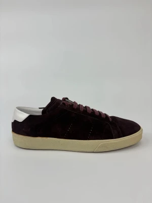 Vinröda Saint Laurent sneakers i mocka - Snygga vinröda sneakers i mocka med vita detaljer på hälen och beige sula. Skorna har klassisk låg profil och matchande vinröda skosnören. Perfekta för dig som gillar stilrena och trendiga sneakers med en twist.
