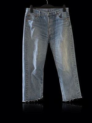 Levi's raka ljusblå jeans med rå kant - Säljer ett par raka jeans från Levi's i ljusblå denim med klassisk femficksdesign och rå, fransad kant nedtill. Jeansen har hög midja och en avslappnad passform. 