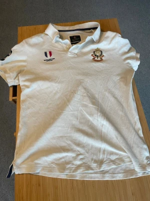 Vit piké från Morris Gentlemens Club - Klassisk vit pikétröja från Morris Gentlemens Club med broderade detaljer på bröstet och krage. Perfekt nu till sommaren! Small men passar medium! Skriv vid frågor!🥂(obs har två pyttesmå fläckar som knappt syns)