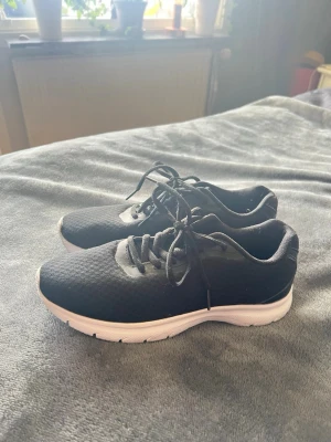 Svarta mesh sneakers med vit sula - Snygga svarta sneakers med ovandel i mesh-tyg och vita, tjocka sulor. Skorna har klassisk snörning och en sportig, stilren look som passar till det mesta. Perfekta för dig som gillar enkel och modern stil.