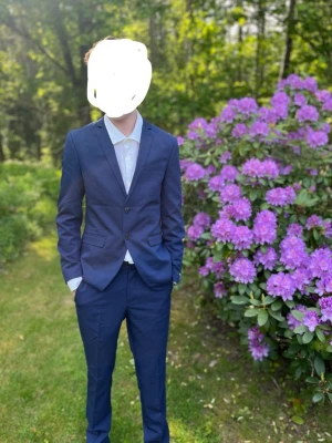 Marinblå kostym från Jack & Jones - Snygg marinblå kostym från Jack & Jones Premium med klassisk tvåknäppt kavaj och matchande byxor. Kavajen har smal passform, fyra knappar vid ärmslut och diskret struktur i tyget. Perfekt för student eller bal. Använd vid ett tillfälle. 