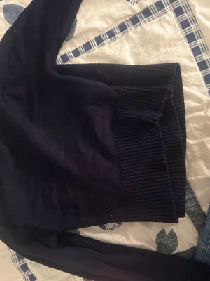 Mörkblå stickad tröja från Gina Tricot - Mörkblå stickad tröja från Gina Tricot med långa ärmar och bred ribbstickad mudd vid midjan. Enkel och stilren design som passar perfekt till jeans eller kjol. Skön och mjuk känsla, perfekt för kyligare dagar.