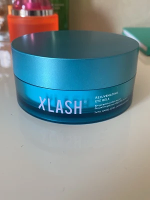 Xlash Rejuvenating Eye Gels - Säljer Xlash Rejuvenating Eye Gels i en snygg blå rund burk. Innehåller ögongel-pads med  30 pairs hyaluronsyra och aminosyror för återfuktning och fräsch känsla runt ögonen. Perfekt för dig som vill pigga upp trötta ögon. Förpackningen är tillverkad i plast.