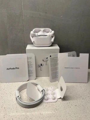 Apple AirPods Pro trådlösa hörlurar - Säljer ett par vita Apple AirPods Pro med laddningsetui, extra silikonpluggar och laddningskabel. Hörlurarna har en stilren och kompakt design, perfekt för dig som vill ha grymt ljud och brusreducering. Allt originaltillbehör och förpackning medföljer.