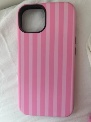 Rosa randigt mobilskal - Snyggt mobilskal i hårdplast med rosa och ljusrosa vertikala ränder. Skalet ger lite Victoria secret vibes och är jättefint och gulligt 💕✨Skalets insida är svart och kan tas av ifall du har iPhone 14. Men om du har iPhone 13 så stannar det kvar 🤗