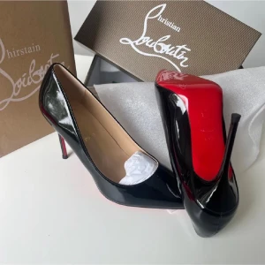 Svarta lackpumps från Louboutin - Snygga svarta pumps i lack från Christian Louboutin med klassisk spetsig tå och ikonisk röd sula. Skorna har hög klack och elegant form, perfekta för att lyfta vilken outfit som helst. Tillverkade i glansigt läder för en lyxig känsla.