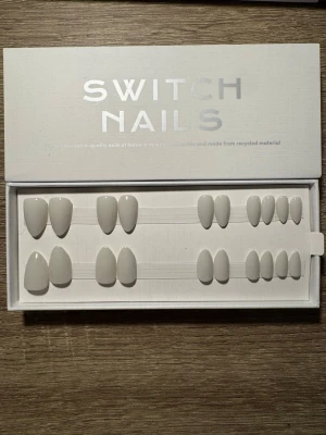 Switch Nails Grey't Match Almond Short - Press-on naglar från Switch Nails i modellen Grey't Match. Naglarna har en kort mandelform och är i en ljusgrå nyans. Tillverkade av återvunnet material för en hållbar look. Perfekt för dig som vill ha snygga naglar snabbt och enkelt. Säljs utan tillbehör.