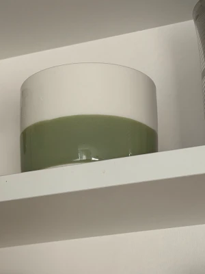 Grönvit glasskål och två vita muggar - Säljer en stilren skål i glas med grön botten och vit ovandel samt två vita keramikkoppar med handtag. Skålen har en rund form och kopparna är lite bulliga med klassisk design. Perfekt för dig som gillar unika köksprylar.
