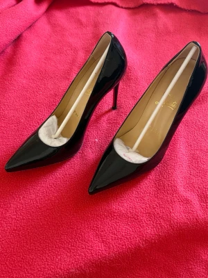 Svarta Kate 100mm  från Christian Louboutin - Säljer ett par klassiska svarta pumps Kate 100mm från Christian Louboutin. Skorna har spetsig tå och hög stilettklack, med den ikoniska röda sulan. Perfekta för dig som vill ha en elegant och tidlös look. Det är även helt oanvända!