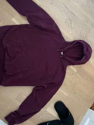Vinröd hoodie med magficka - Säljer en vinröd hoodie från Gina tricot med klassisk magficka och dragsko i huvan. Hoodien har en avslappnad passform och är gjord i mjukt bomullsmaterial. Perfekt för en chill och stilren look.
