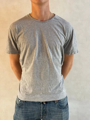Ralph Lauren T-Shirt - Enkel grå t-shirt i mjuk bomull med rund hals och korta ärmar. Perfekt till jeans eller shorts för en avslappnad stil. T-shirten har en normal passform och är helt utan tryck eller mönsterk.