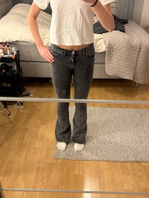 Grå bootcut jeans från Gina Tricot - Säljer ett par snygga grå bootcut jeans från Gina Tricot. Jeansen har klassisk femficksmodell, medel/ låg midja och utsvängda ben. Materialet är mjukt denim med en tvättad look som ger en cool vintagekänsla. Perfekta till en avslappnad stil.