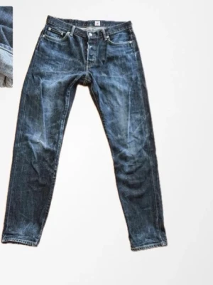 Blå raka jeans med slitningar - Snygga blå jeans med raka ben och coola slitningar. Klassisk femficksmodell med knappgylf och tydliga tvättade detaljer. Perfekta för en avslappnad streetstil och passar till det mesta. Tillverkade i denim.