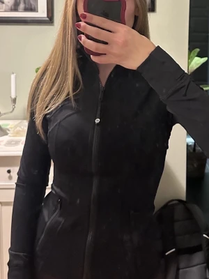 Svart träningsjacka från Lululemon - Säljer svart luluemon define i nytt skick som är köpt här på Plick. Råkade köpa två likadana därav säljer jag en. Det är den långa modellen! Säljer för samma pris som jag köpte den för! Storlek 4 