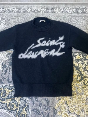 Svart Saint Laurent stickad tröja - Den kända ysl tröjan för fem gånger mindre pengar. Detta är ett måste i din garderob för både stil och komfort. Tröjan har fantastisk kvalitet för sitt låga pris, och jag köpte den från en privat agent för nästan dubbla priset. Först till kvarn!! 🔥🫡  Priset kan diskuteras, men endast med seriösa köpare.