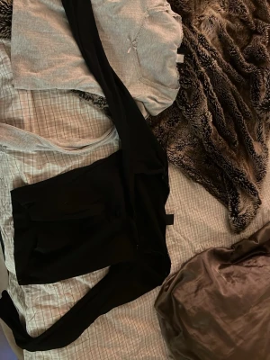 Grå loungewear set med spetskant - Mysigt loungewear set med en ljusgrå långärmad topp med spetskant vid halsen och liten rosett framtill. Tillhörande svarta byxor med resår i midjan. Perfekt för chill dagar hemma eller när du vill vara bekväm men ändå söt. De är två stycken❤️