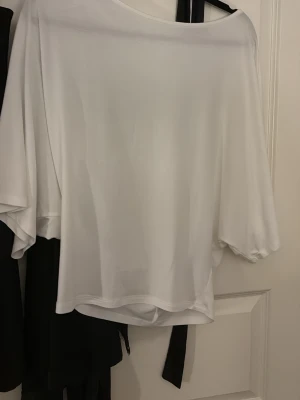 Vit offshoulder topp från Nelly - Säljer en vit offshoulder topp från Nelly i mjukt och lätt material. Toppen har vida trekvartsärmar och en lös passform som ger en avslappnad och trendig look. Perfekt att styla med jeans eller kjol för en cool vibe. större ärmarna och tajtare vid midjan