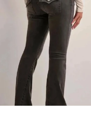 Grå bootcut jeans med fickdetaljer - Ett par helt oanvända true religion jeans i modellen joey alltså bootcut. Mörkgråa i storlek 25/32.