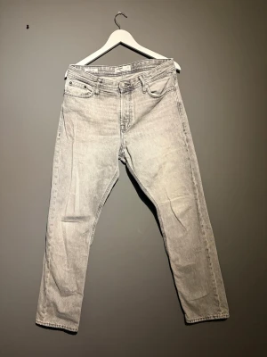 Grå loose fit jeans Jack & Jones - Säljer ett par grå loose fit jeans från Jack & Jones, modell Chris. Jeansen har raka ben och klassisk knappgylf. Perfekta för en avslappnad och trendig stil. Materialet är mjukt denim i bomull.