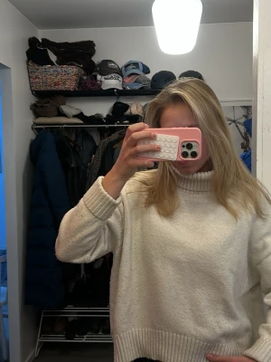 Vit stickad polotröja - Mysig vit stickad polotröja med breda ribbade muddar vid ärmslut och nederkant. Tröjan har en hög krage och en avslappnad passform, perfekt för kalla dagar. Enkel och stilren design som passar till det mesta. 