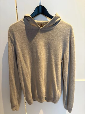 OSCAR JACOBSSON KASHMIRHOODIE - Beige kashmirblandad hoodie från Oscar Jacobsson. Storlek S. Skönt material och fin passform. En liten liten defekt i kragen, men inget som syns och går självklart att lösa. Hör av er vid fler frågor, Walter.