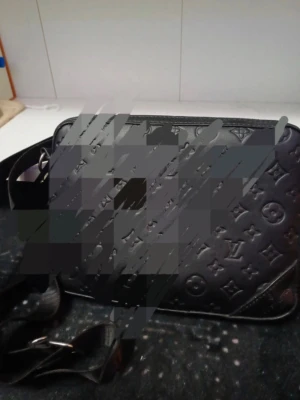 Svart axelväska Louis Vuitton - Snygg svart axelväska från Louis Vuitton i präglat läder med det klassiska monogrammönstret. Väskan har justerbar axelrem i textil och silverfärgade metalldetaljer. Perfekt för dig som vill ha en stilren och lyxig accessoar.