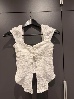 Vit ribbad linnetopp  - Supersöt vit linnetopp med axelband och ribbad struktur. Perfekt för varma dagar och enkel att styla med jeans eller kjol.