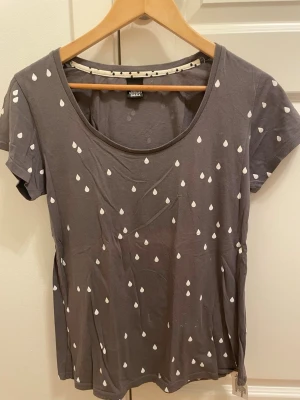 Grå t-shirt med vita droppar Cheap Monday - Grå t-shirt från Cheap Monday med vita droppformade prickar över hela plagget. T-shirten har rund halsringning och korta ärmar. Tillverkad i mjuk bomull som känns skön mot huden. Perfekt för en avslappnad och trendig stil.