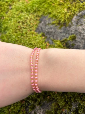 Rosa pärlarmband i dubbel design - Två elastiska armband med små rosa pärlor i en enkel men snygg design. Perfekta att bära tillsammans eller var för sig för en söt och trendig look. Passar dig som gillar färgglada accessoarer och vill addera lite extra till din outfit.