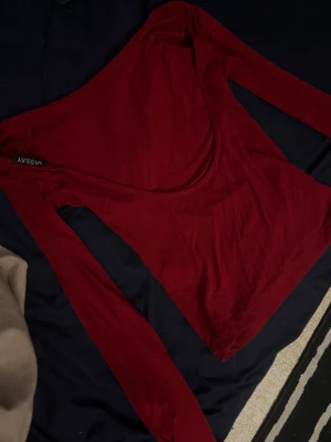 Vinröd långärmad topp missäy - Snygg vinröd öppen rygg långärdmad topp. Tillverkad i mjukt och stretchigt material som sitter tajt mot kroppen. Perfekt att styla med jeans eller kjol för en trendig look.