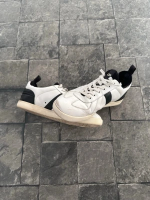 Dior homme B01 ”GAT” sneakers 2004-2007 - Snygga sneakers från Dior i svart och vitt.  Skorna är använda och har en del märken och slitage (se bilder), men är fortfarande i bra skick och har mycket kvar att ge. De kan dessutom enkelt fräschas upp och fixas till hos en skräddare eller skomakare om man vill.  Storleken är 41.5, men de kan passa upp till 43.5 om du använder dem utan insulan. Observera🛑 att insulan saknas.  Självklart är skorna äkta.