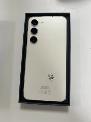Samsung Galaxy s23  v - Snygg Samsung GalaxyS23  Android-telefon färg med stilren design. Baksidan har tre kameror i rad och en slät, glansig finish. Metallramen ger en premiumkänsla och knapparna sitter på sidan. Perfekt för dig som vill ha en modern och kraftfull smartphone.