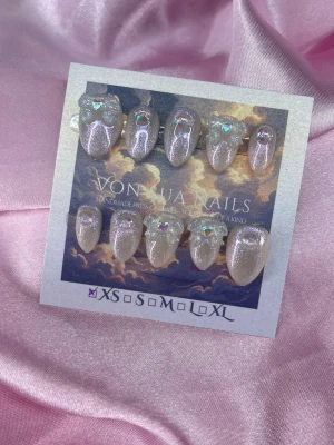 Tenshi (XS);Short Almond - Snygga handgjorda press-on naglar i skimrande glittereffekt. Naglarna har en kort almond form och är dekorerade med pärlliknande stenar och holografiska detaljer för extra wow-känsla. Perfekt för dig som vill ha unika och snygga naglar.XS: 14 mm, 11 mm, 11,5 mm, 10 mm, 8 mm 