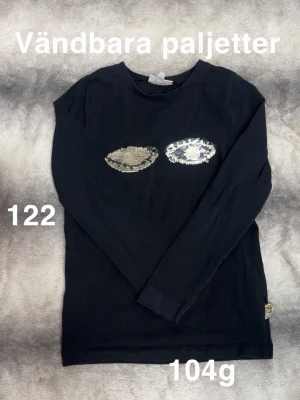 Svart långärmad topp med paljetter - Svart långärmad topp med vändbara paljetter i silver och guld framtill. Rund halsringning , perfekt för en trendig look.🌸 Fint använt skick. Vändbara paljetter. Storlek 122