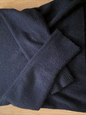 Mörkblå stickad tröja med ribbade muddar - En enkel och stilren mörkblå stickad tröja med långa ärmar och ribbade muddar vid ärmslut och nederkant. Perfekt för lager-på-lager och passar till det mesta. Materialet känns mjukt och värmande.