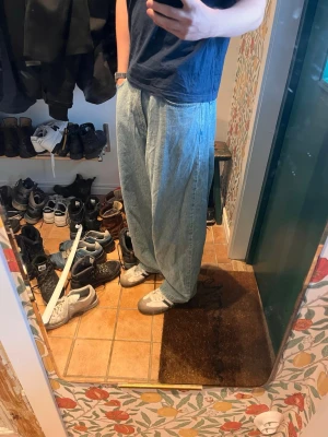 Baggy ljusblå jeans från Moschino - Säljer ett par riktigt snygga baggy jeans från Moschino Couture! i ljusblå denim. Jeansen har en avslappnad passform med breda ben och klassisk femficksdesign. Perfekta för dig som gillar streetwear och vill ha en unik look.